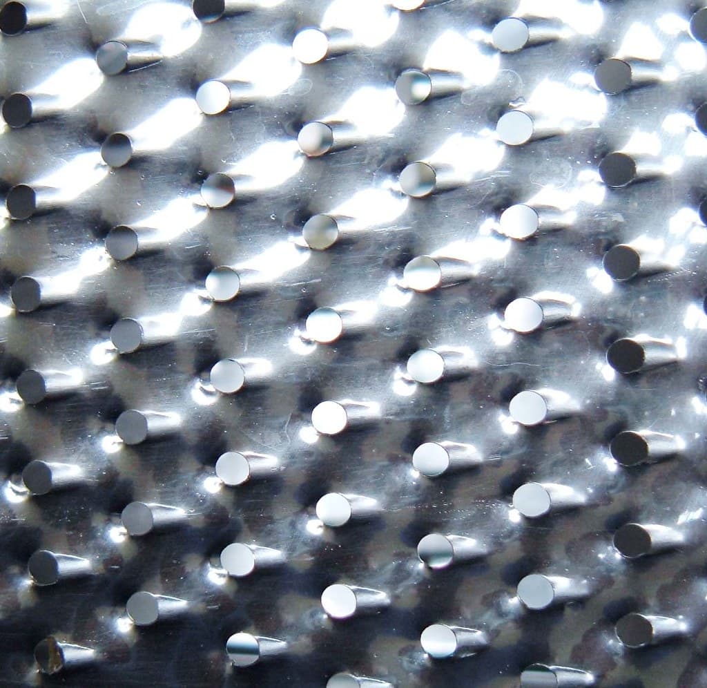 Close-up of stainless steel pipe section showing uniform surface with minor water droplets, installed in a coastal industrial facility.