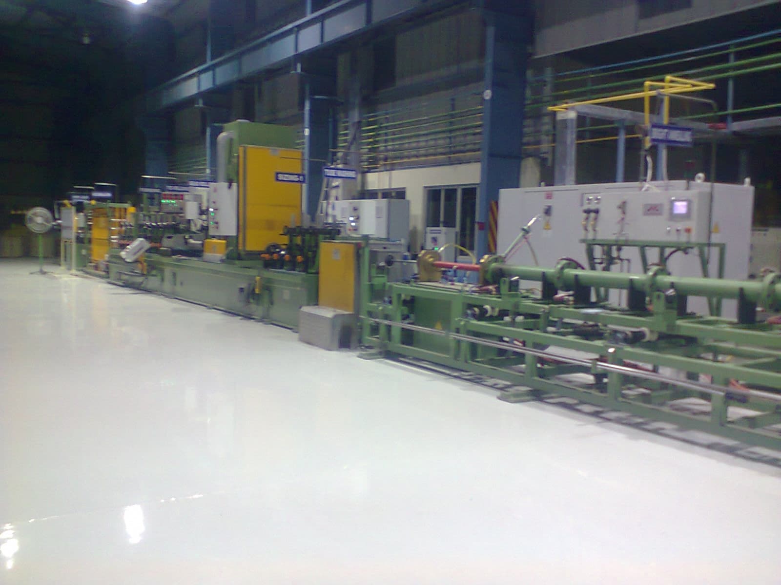 CNC lathe cutting a stainless steel shaft with visible coolant flow and chip formation