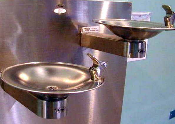 CNC lathe machining a stainless steel shaft with visible coolant flow and chip formation