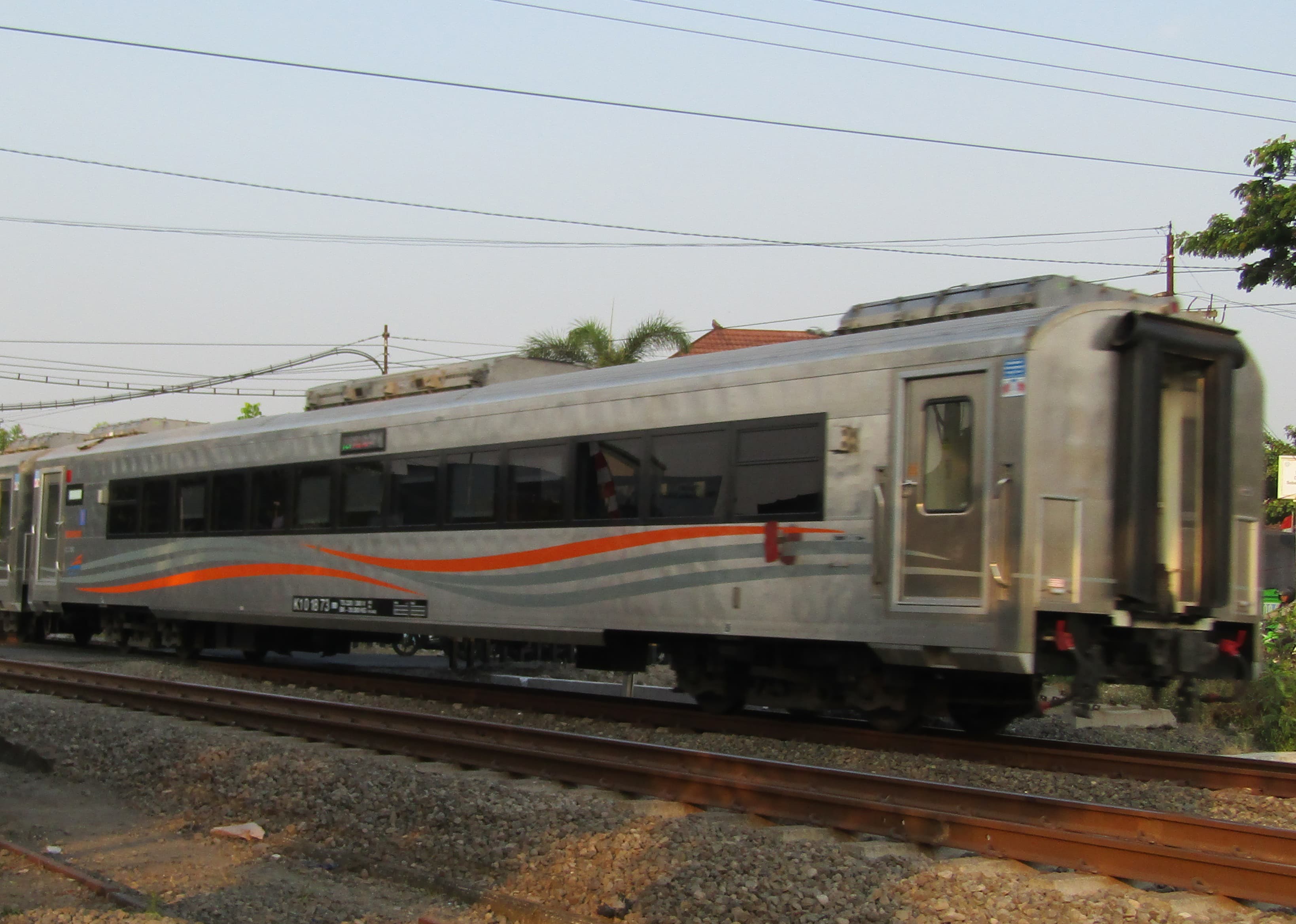 Close-up of a brushed stainless steel sheet with visible linear grain pattern and calibrated surface measurement tool on edge